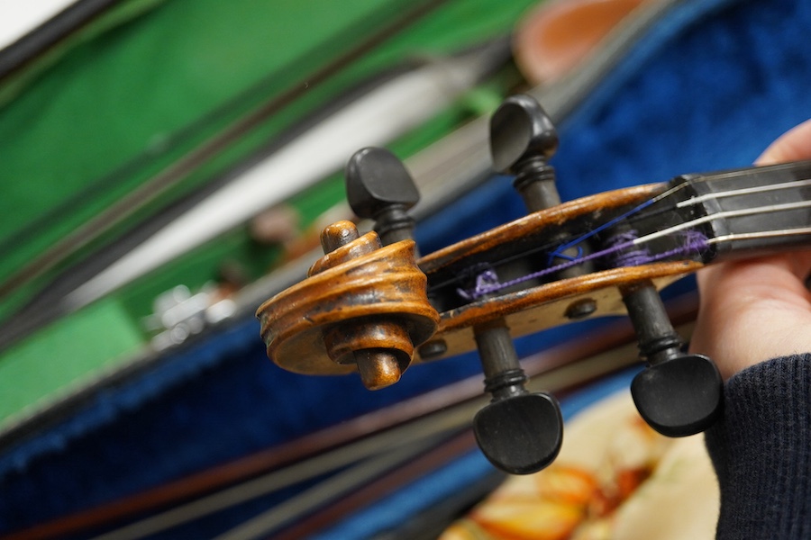 Four cased violins; an early 20th century violin, body 36cm, fitted with a microphone pick up taking a quarter inch jack plug, an early 20th century half size violin, body 32cm, and two student violins. Condition - poor